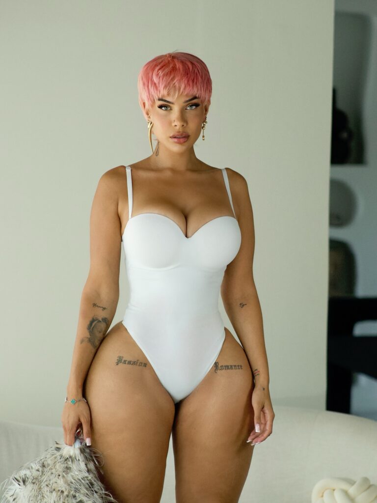 Amirah Dyme posing in a one-piece bodysuit