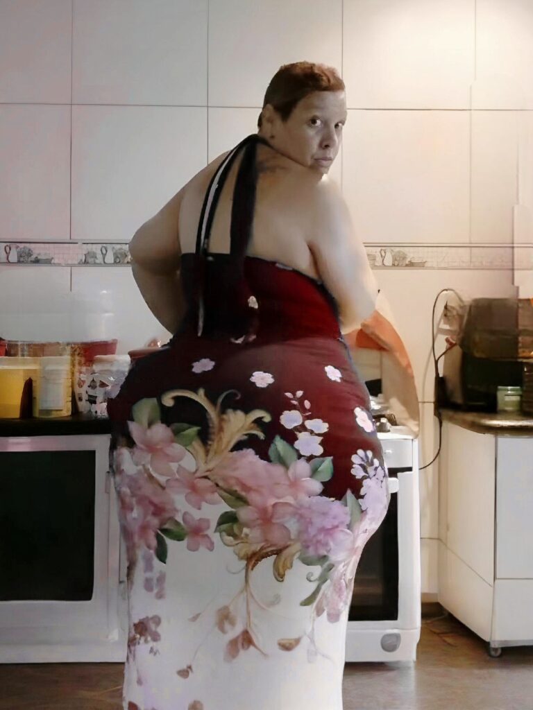 Kiki Costa posant de dos en robe, dans une cuisine